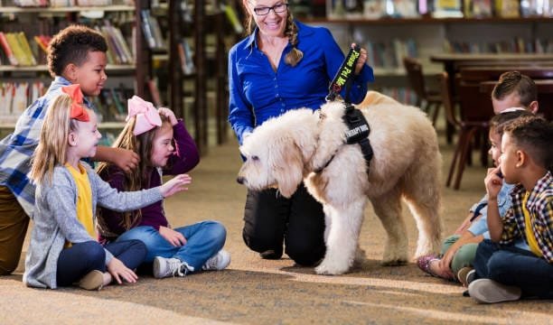Enfants dans la bibliothèque avec lecture de chien d’assistance