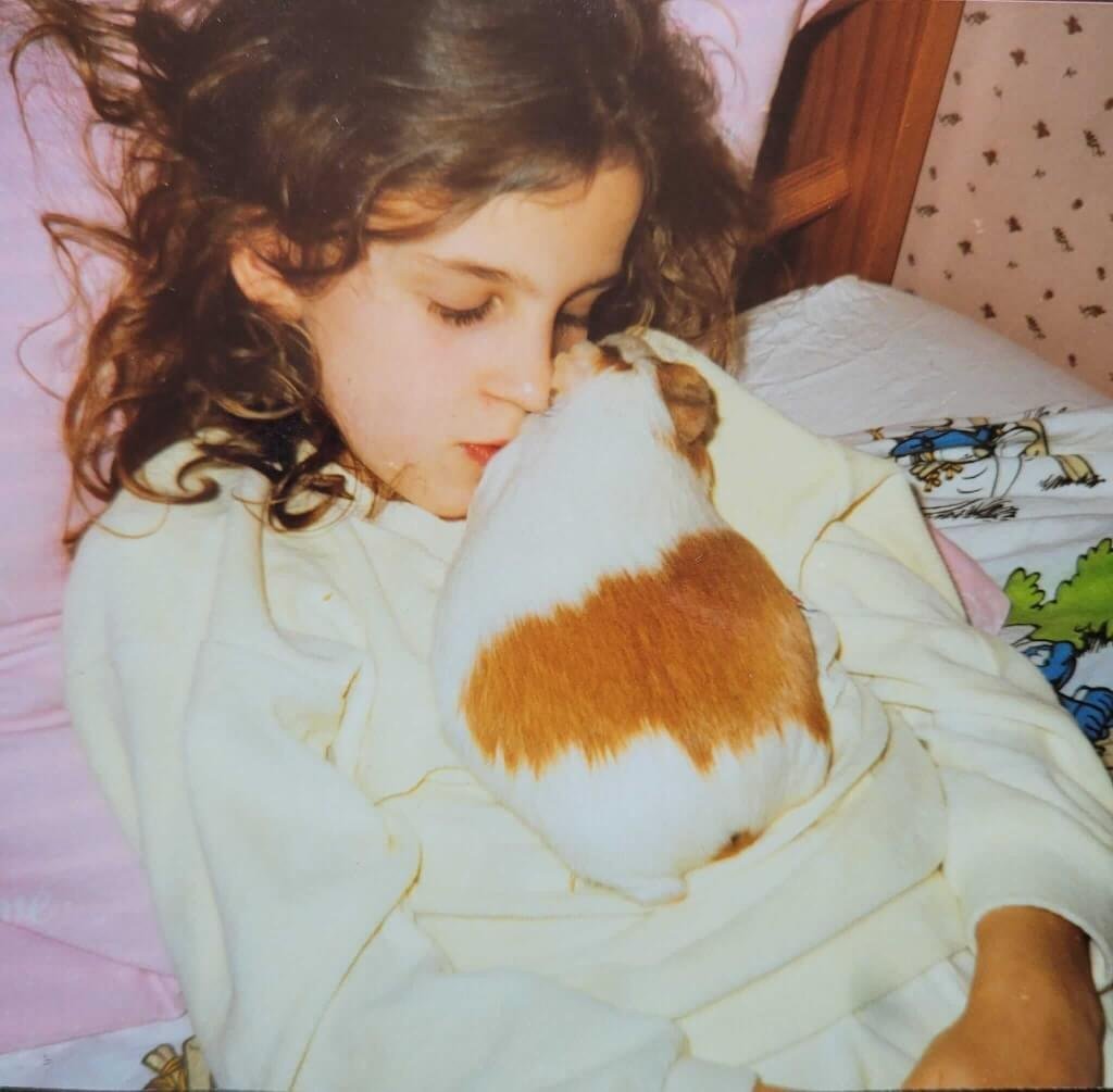 Sandra Daulon enfant calinant sur son lit sa première cochon d'inde Câline gestante